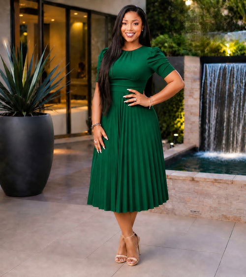 Solid green Pleated Elegance Midi Dress with a structured bodice and pleated skirt, showcased outdoors near a water feature.