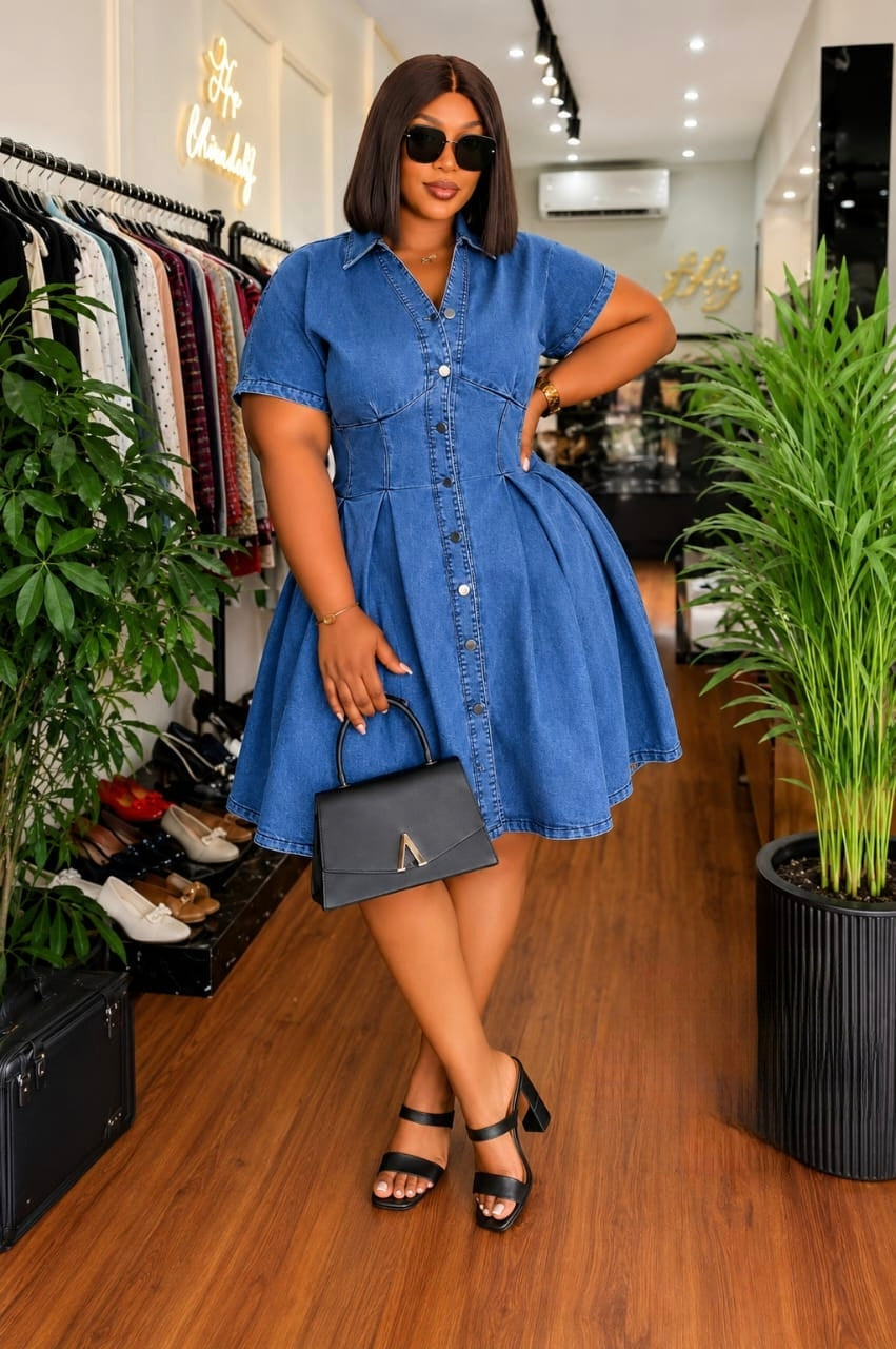 Model wearing a denim button-up flare mini dress with short sleeves and a collared neckline, accessorized with sunglasses and a handbag.