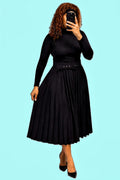 Black pleated skirt with a belted waist, featuring a flowing silhouette and worn with a fitted top.