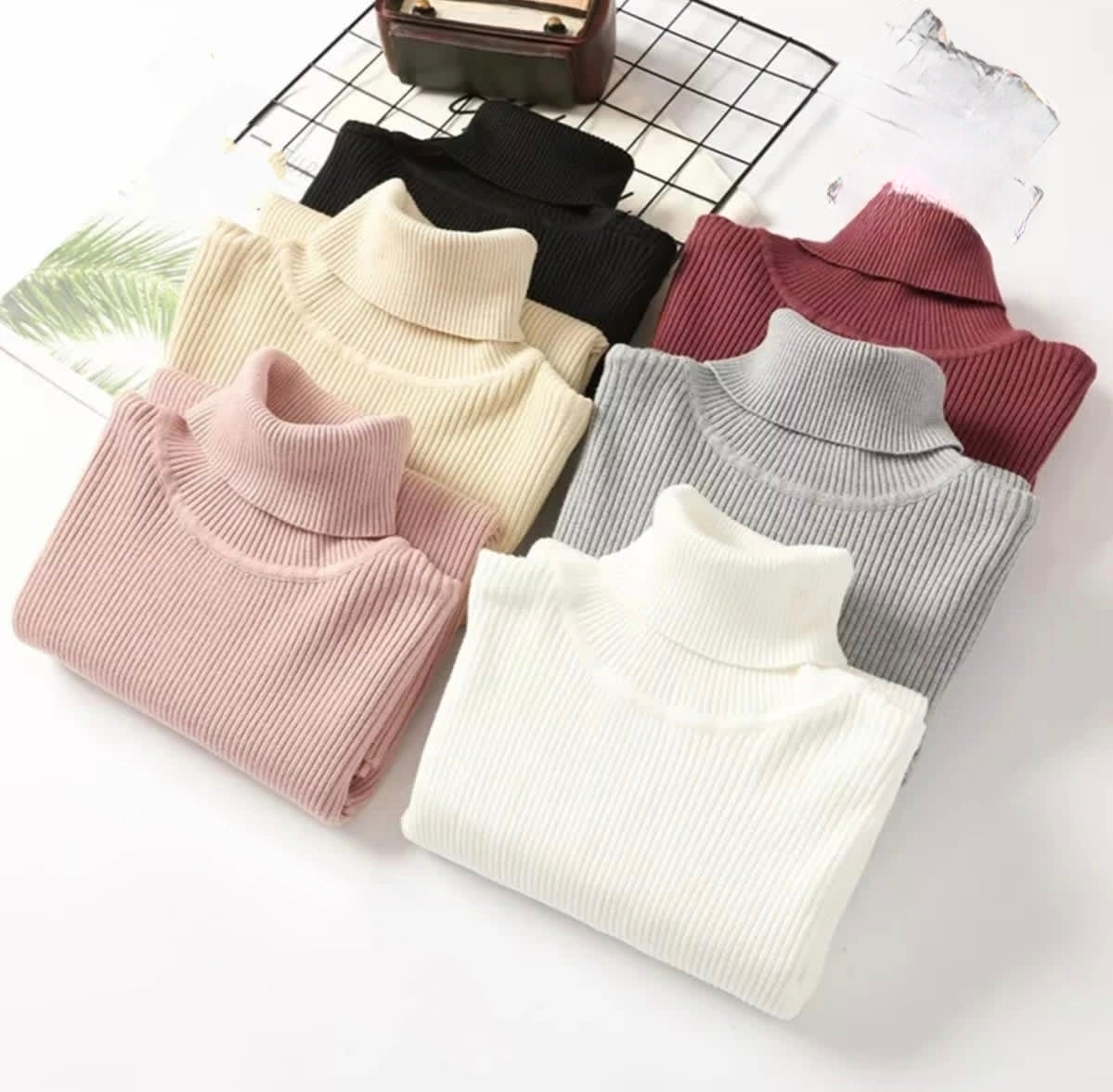 Collection of ribbed turtleneck sweaters in various colors, featuring high necklines and a sleek, fitted design.