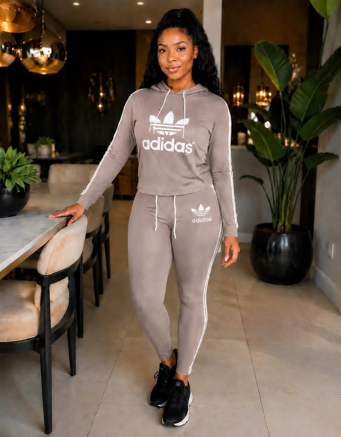 Two-piece Adidas tracksuit set featuring a hoodie with drawstring closure and joggers with side stripes.