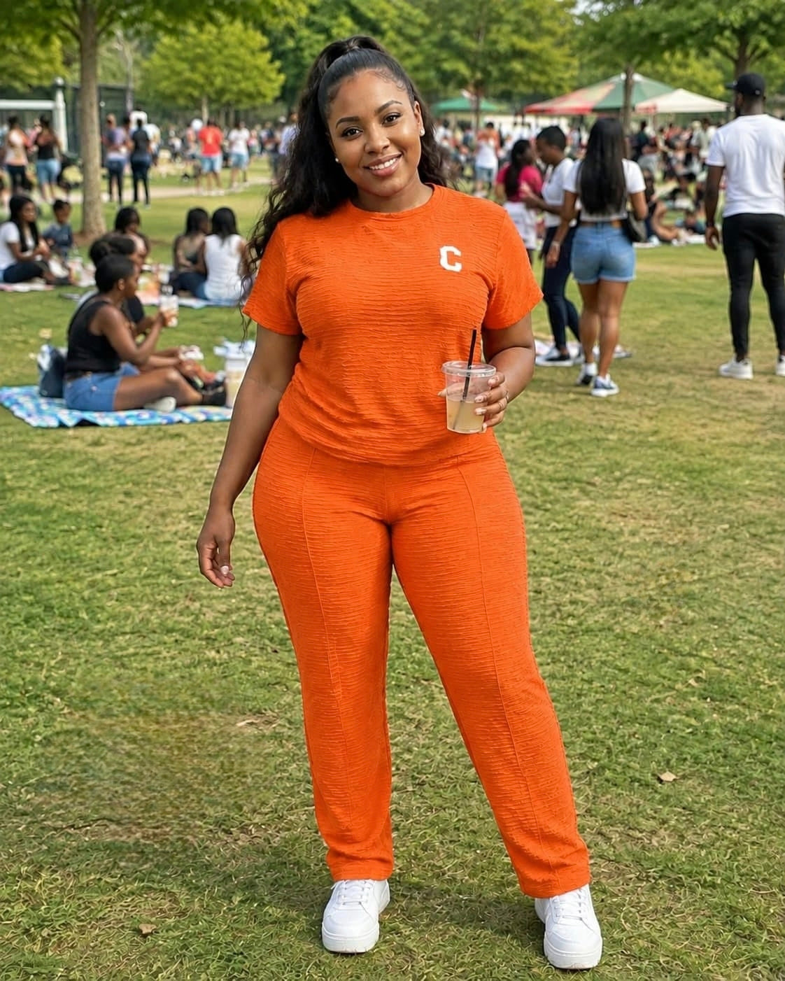 Model wearing the vibrant orange Textured Two-Piece Lounge Set KT with a bold emblem, styled with white sneakers outdoors.