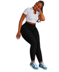 Person wearing black stretch pants with a high waist, paired with a white cropped shirt and blue sneakers.